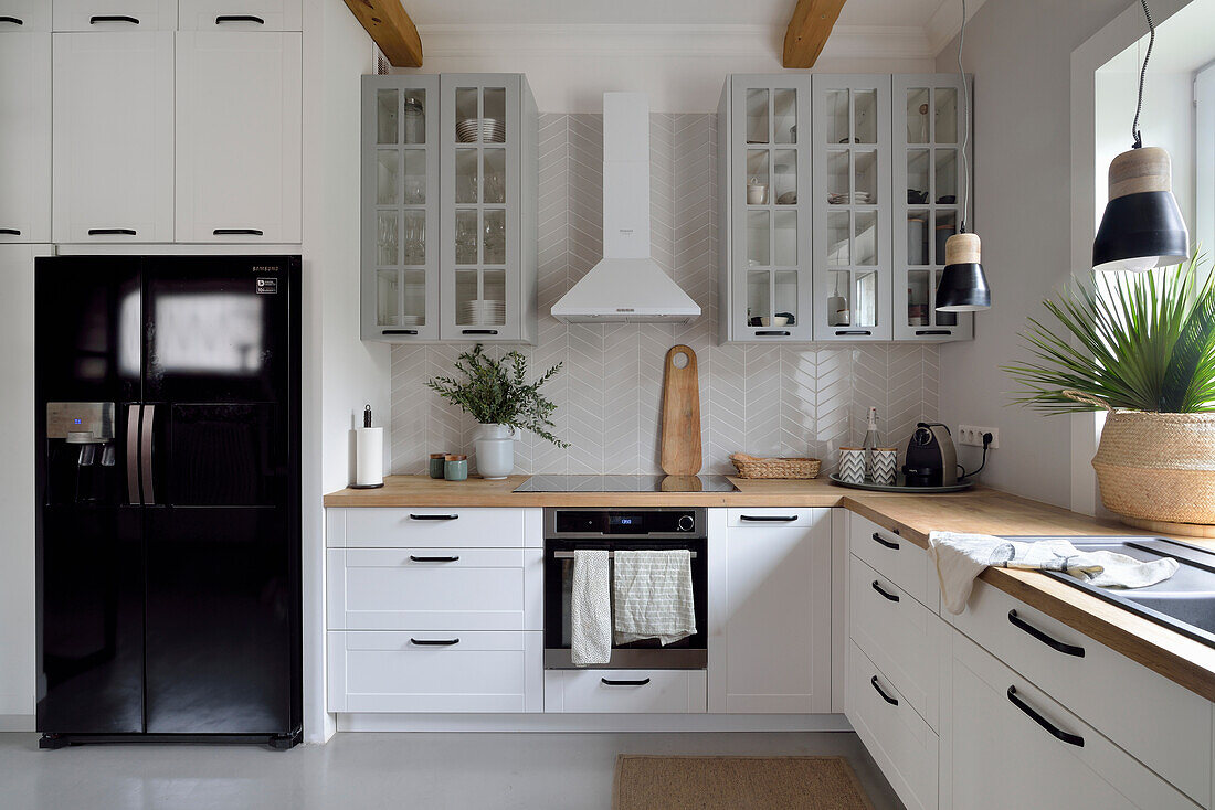 White kitchen with wooden worktop and black side-by-side refrigerator