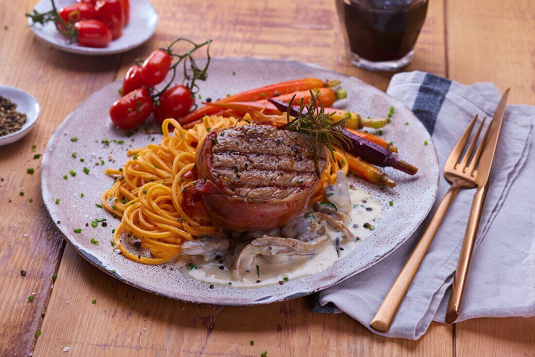 Fillet of beef wrapped in ham with noodles and vegetables