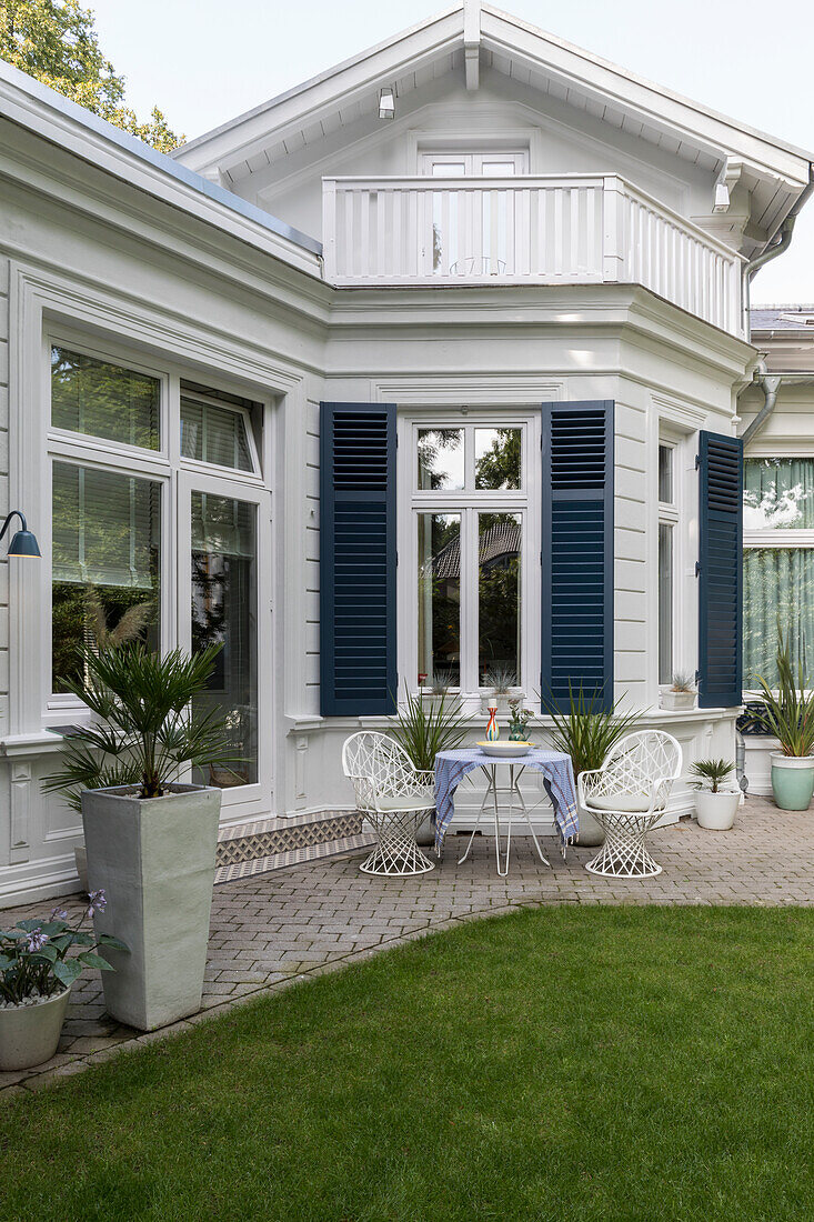 Runder Tisch mit Vintage Stühlen und Pflanzkübel auf der Terrasse