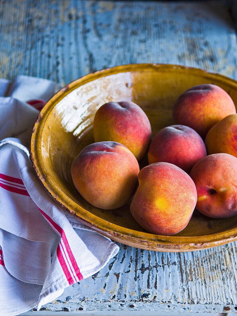 Peaches in a bowl, tea towel next to it