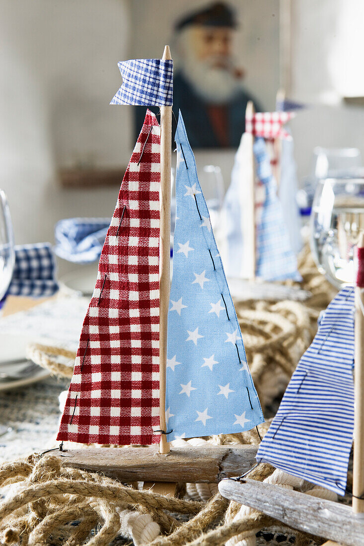 DIY sailboat made of driftwood and garland made of ropes as maritime table decoration