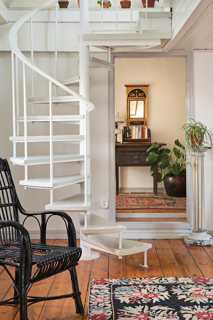 Weiß gestrichene Wendeltreppe, im Hintergrund antike Konsole und Wandspiegel