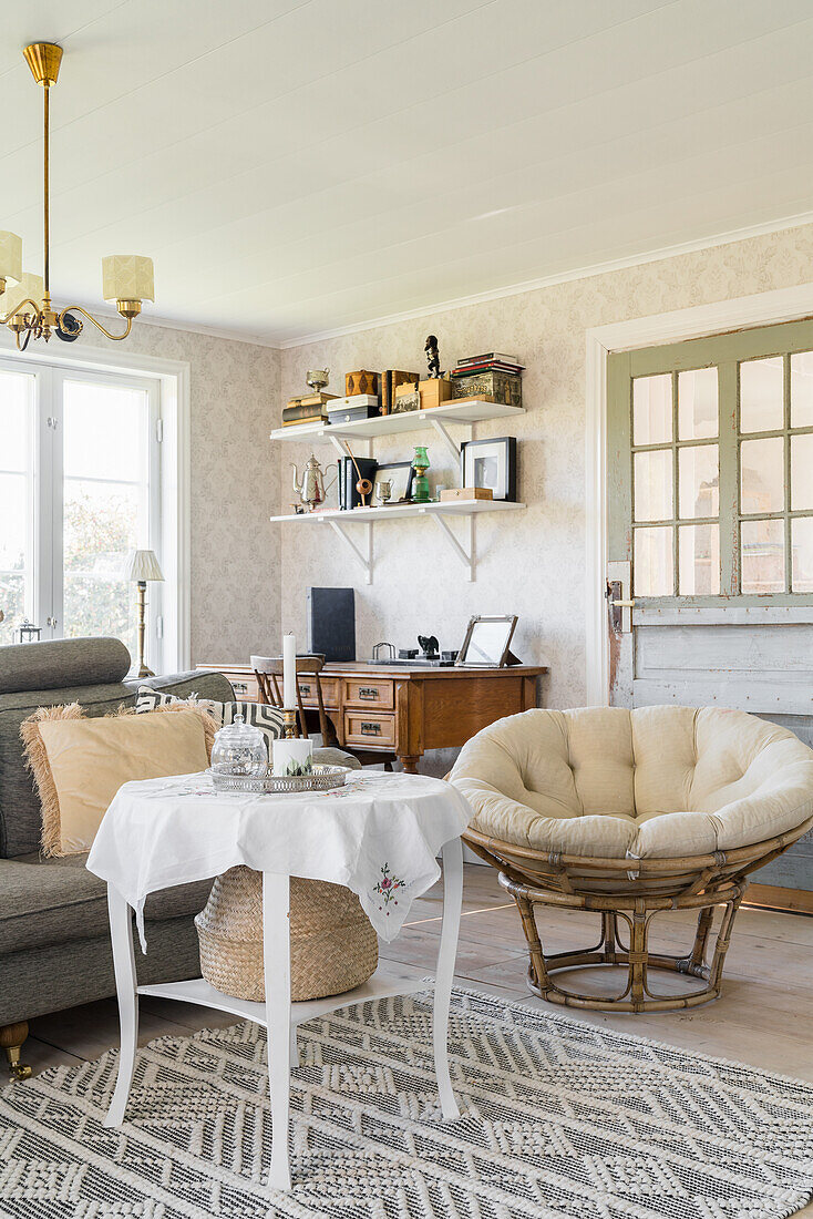 Round table on grey and white patterned rug and armchair in Scandinavian-style living room