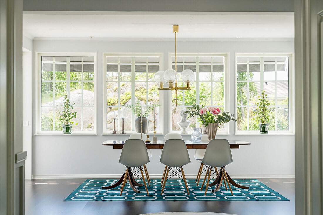 Glazed veranda with dining table and white classic chairs on a turquoise blue carpet