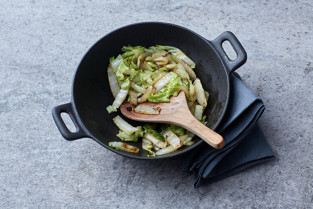 Chinese cabbage being sautéed in a wok (stir-frying)