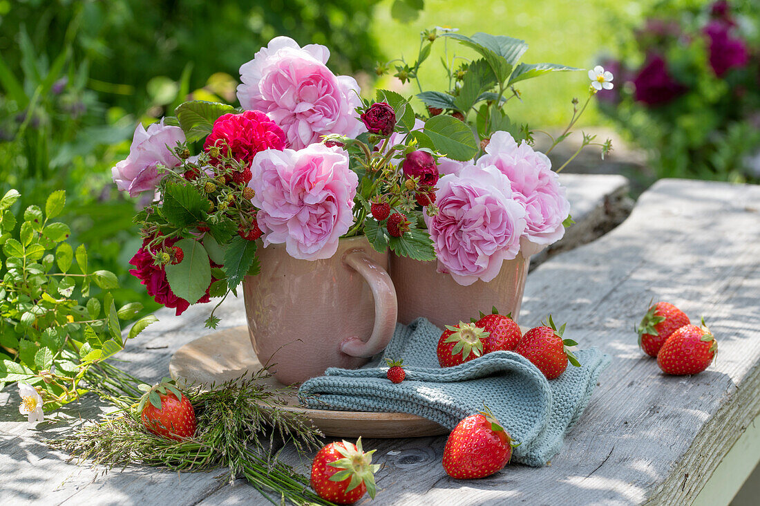 Rosenstrauß mit Erdbeerzweigen auf Gartentisch