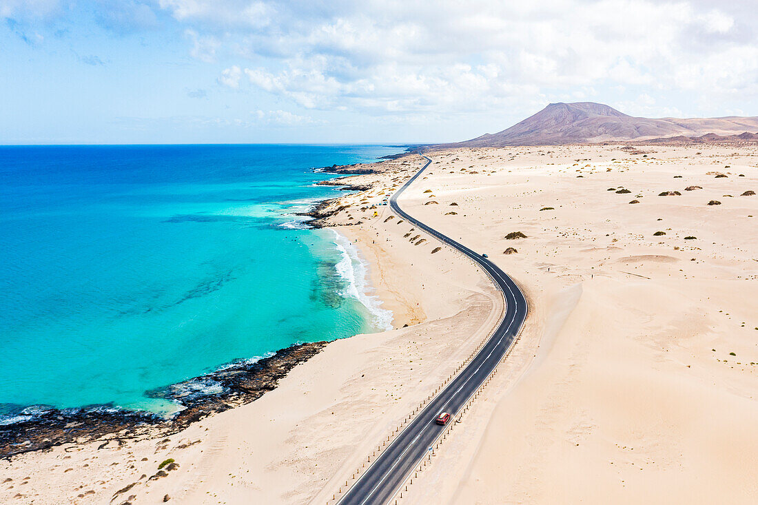 Luftaufnahme einer Straße durch die Wüste mit Blick auf das kristallklare Meer, Corralejo Naturpark, Fuerteventura, Kanarische Inseln, Spanien, Atlantik, Europa