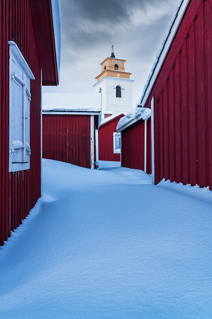 Clouds over the snow covered red cottages and bell tower, Gammelstad Church Town, UNESCO World Heritage Site, Lulea, Sweden, Scandinavia, Europe