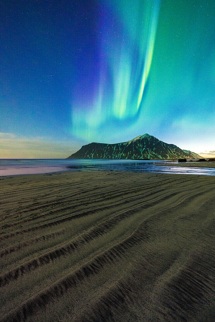 Der raue Sand des Skagsanden-Strandes wird von den grünen Lichtern der Aurora Borealis (Nordlichter) beleuchtet, Flakstad, Lofoten, Norwegen, Skandinavien, Europa