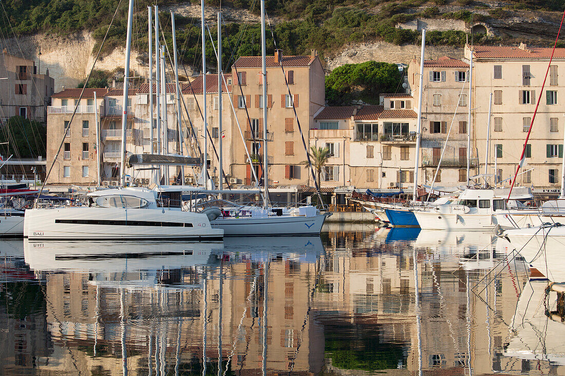 Blick auf den Hafen bei Sonnenaufgang, Yachten spiegeln sich im ruhigen Wasser, Bonifacio, Corse-du-Sud, Korsika, Frankreich, Mittelmeer, Europa