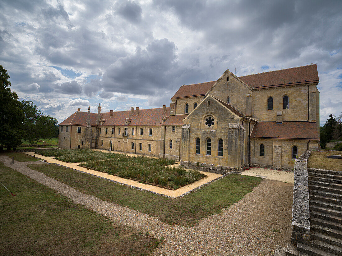 Garden and the exterior of the ancient Noirlac Abbey on a cloudy day, Cher, Centre-Val de Loire, France, Europe