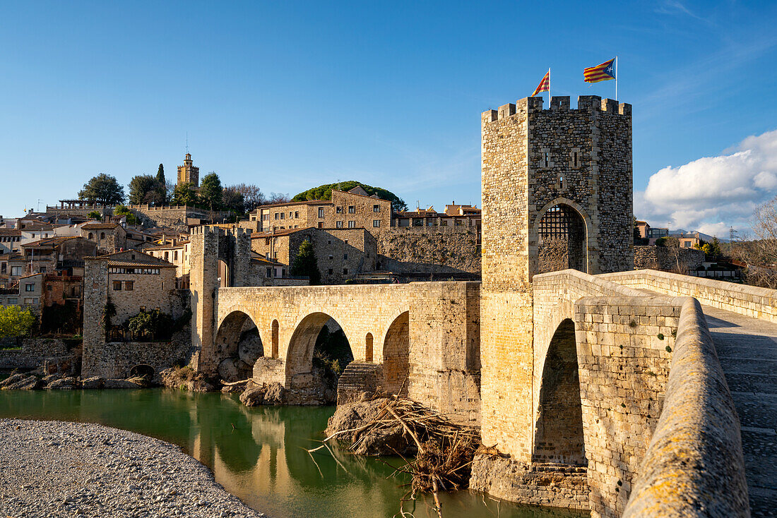 Besalu historische mittelalterliche Stadt mit katalanischen Flaggen auf dem steinernen Brückenturm über den Fluss El Fluvia, Besalu, Katalonien, Spanien, Europa