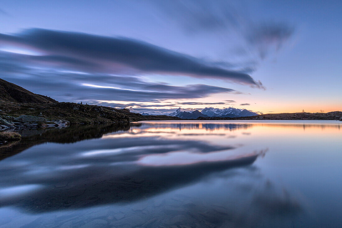 Crazy clouds reflected in the Arcoglio Lake at sunrise, Valmalenco, Valtellina, Lombardy, Italy, Europe