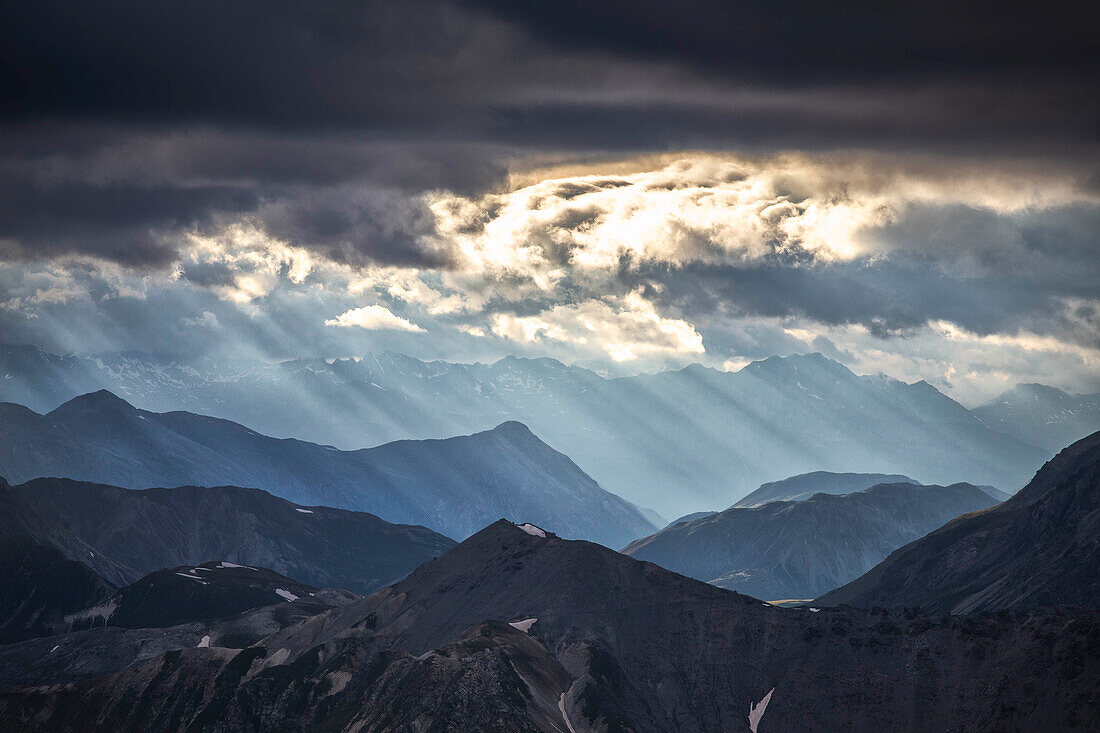 Sonnenstrahlen filtern zwischen schwarzen Wolken bei Sonnenuntergang, Stilfserjochpass, Stilfserjoch-Nationalpark, Valtellina, Lombardei, Italien, Europa