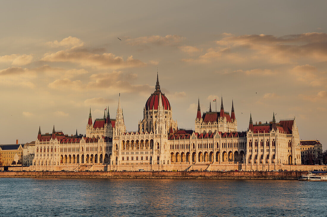 Neogotisches Gebäude des Orszaghaz-Parlaments und Blick auf die Donau bei Sonnenuntergang, mit Wolken darüber, UNESCO-Weltkulturerbe, Budapest, Ungarn, Europa