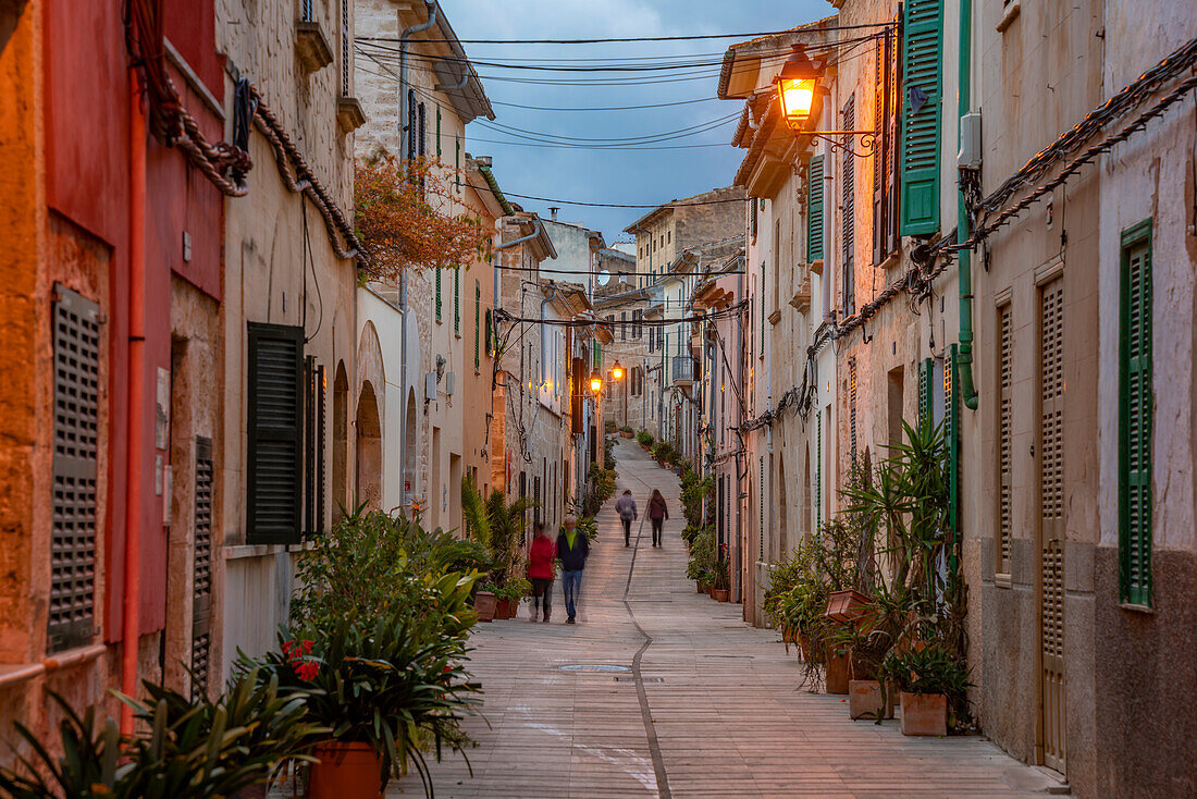 People in street in narrow street at dusk in the old town of Alcudia, Alcudia, Majorca, Balearic Islands, Spain, Mediterranean, Europe