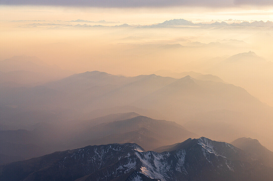 Luftaufnahme des Nebels bei Sonnenuntergang über den majestätischen Lepontinischen Alpen und dem Monte Rosa in den Wolken, Blick aus dem Flugzeug, Schweiz, Europa