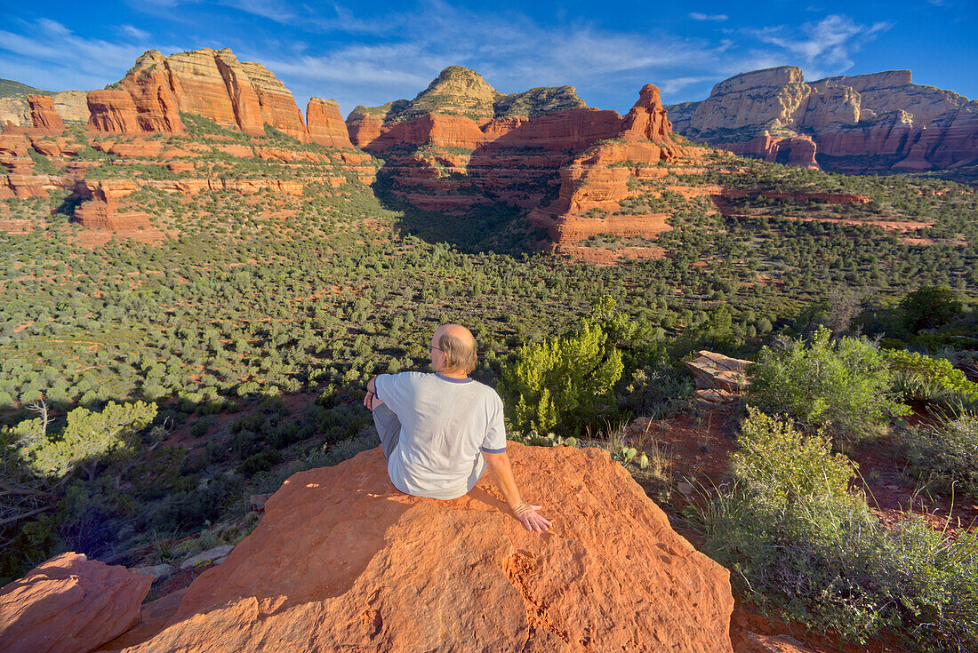 Ein Mann sitzt auf dem Gipfel des Mescal Mountain und überblickt den Deadmans Pass in Sedona, Arizona, Vereinigte Staaten von Amerika, Nordamerika