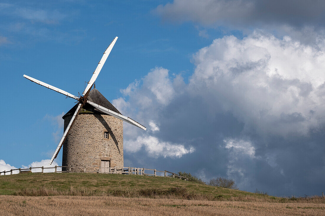 Windmühle auf einem Hügel mit blauem Himmel und weißen Wolken, Normandie, Frankreich, Europa