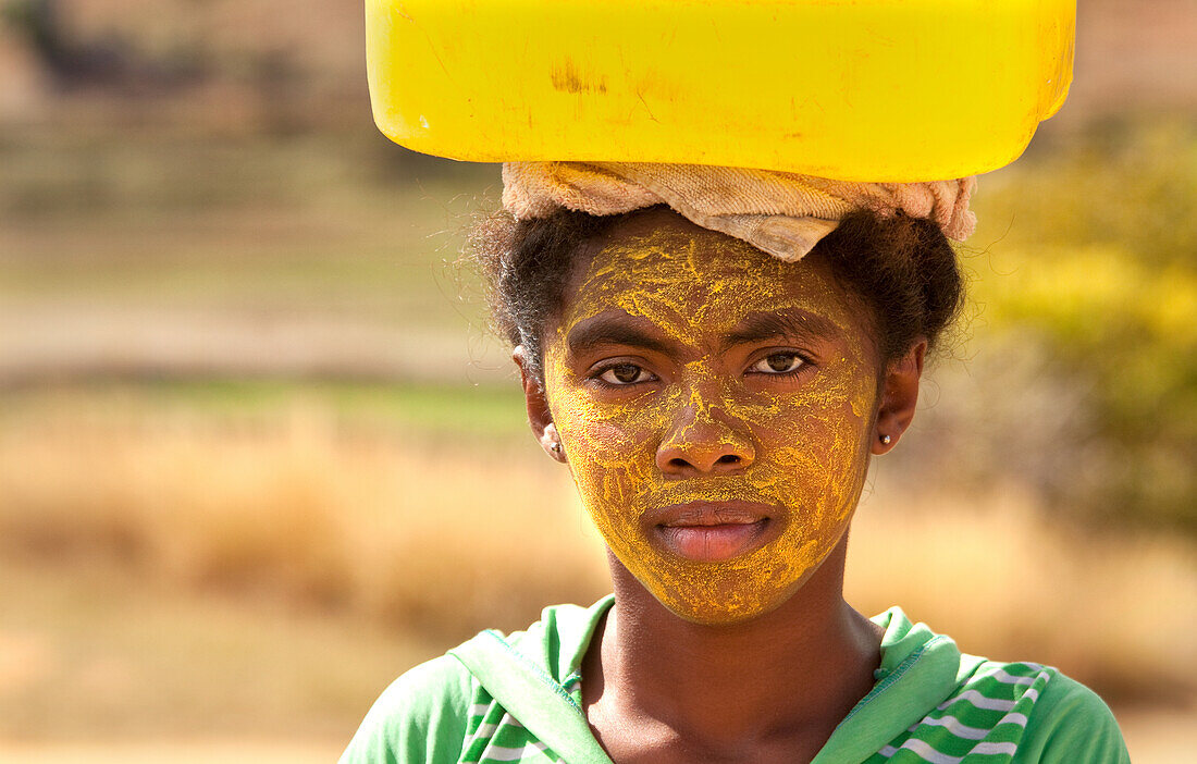 Porträt einer Frau, die Wasser trägt und ihr Gesicht zum Schutz vor der Sonne bemalt, Isalo, Madagaskar, Afrika