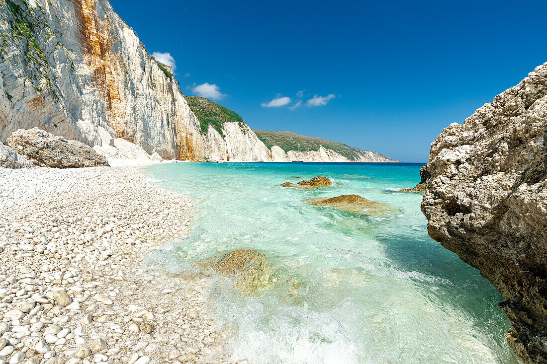 Die Wellen des türkisblauen Meeres umspülen die weißen Steine am Strand von Fteri, Kefalonia, Ionische Inseln, Griechische Inseln, Griechenland, Europa
