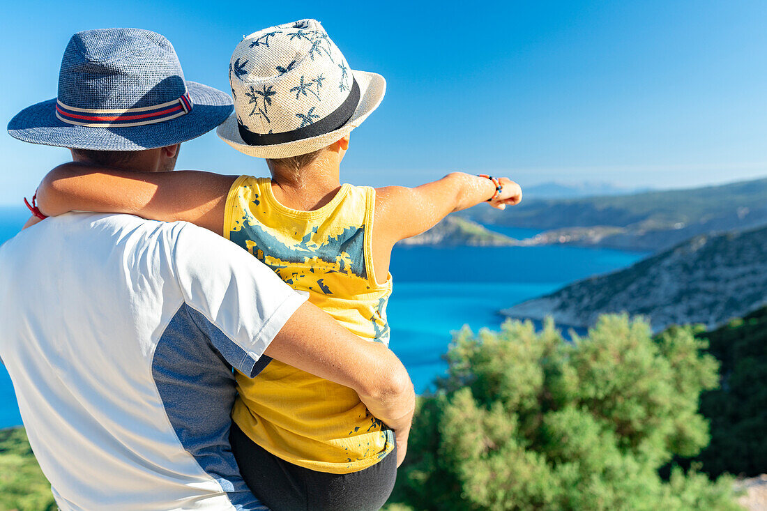 Glücklicher Vater mit süßem kleinen Jungen bewundert das Meer am Strand von Myrtos von der Küste aus, Kefalonia, Ionische Inseln, Griechische Inseln, Griechenland, Europa