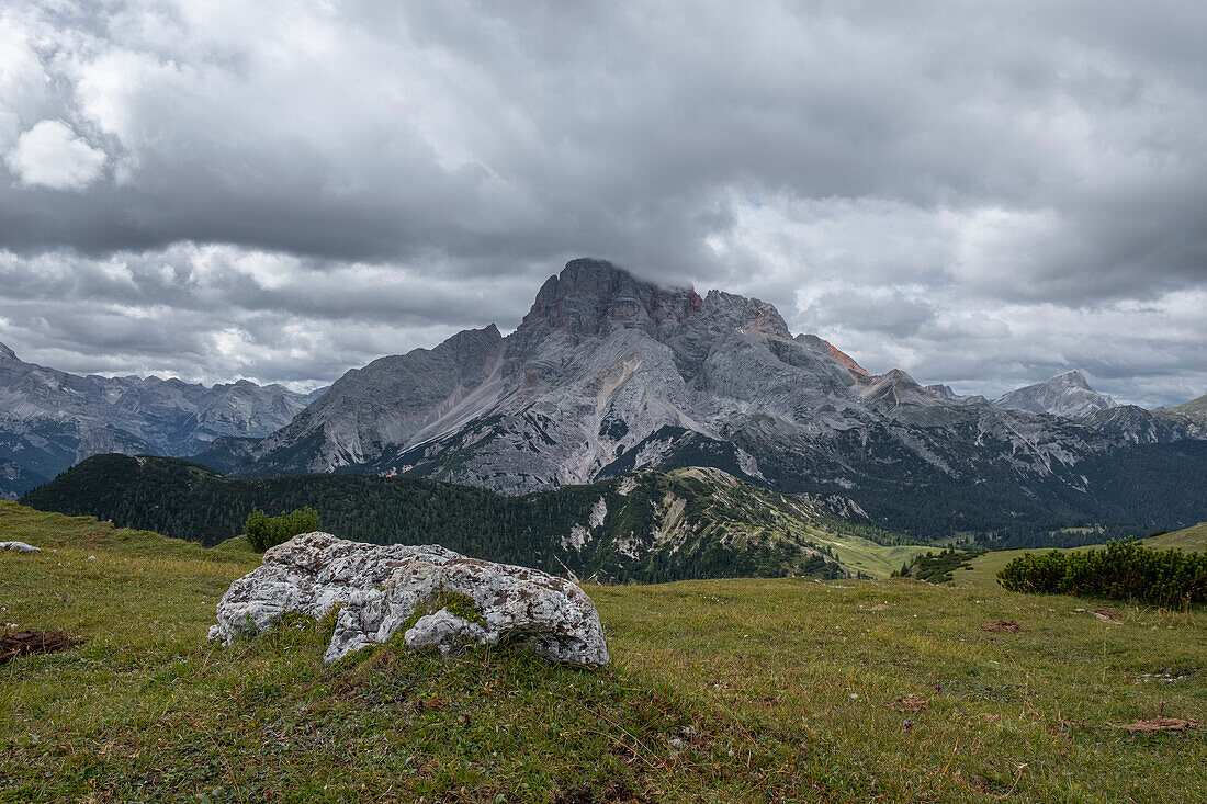 Panorama der Croda Rossa D'ampezzo mit Weiden und einem einzelnen Felsen im Vordergrund und einem bewölkten Himmel, Dolomiten, Italien, Europa