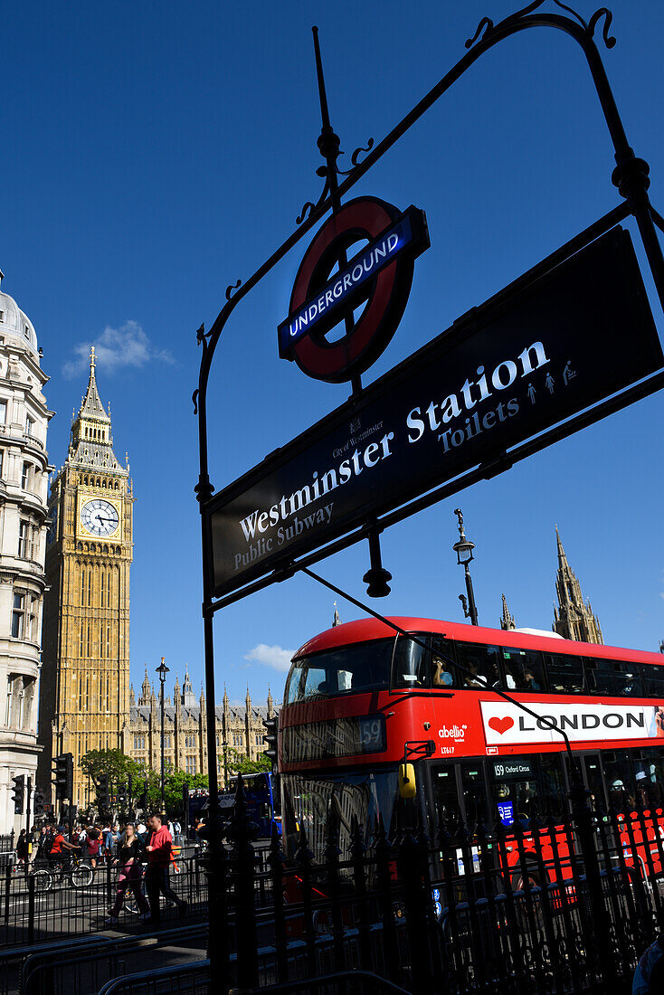 A red London bus and entrance to Westminster tube station, Big Ben (Elizabeth Tower) in the background, London, England, United Kingdom, Europe