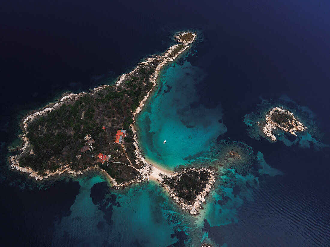 Drohne über einer kleinen Insel mit Haus, grüner Vegetation und felsiger Küstenlinie im Mittelmeer auf der Halbinsel Chalkidiki, Griechenland, Europa