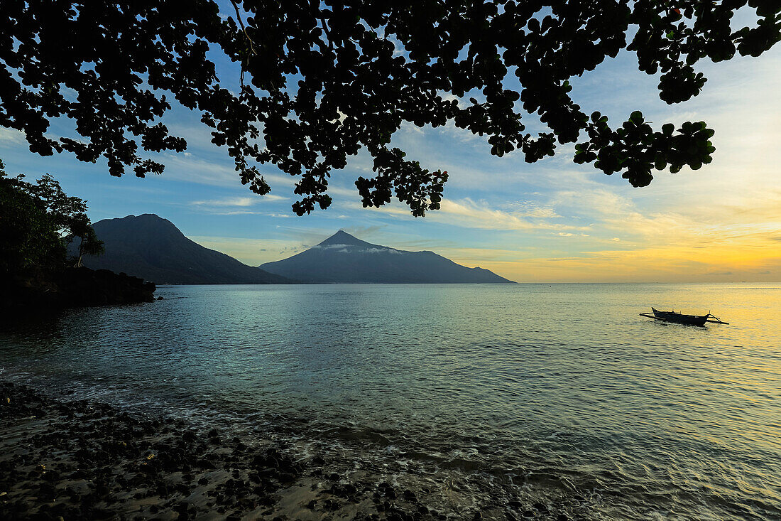 Sonnenuntergang am Strand von Kalea mit Blick auf Kanu und Vulkan Karangetang, Kalea, Siau-Insel, Sangihe-Archipel, Nordsulawesi, Indonesien, Südostasien, Asien