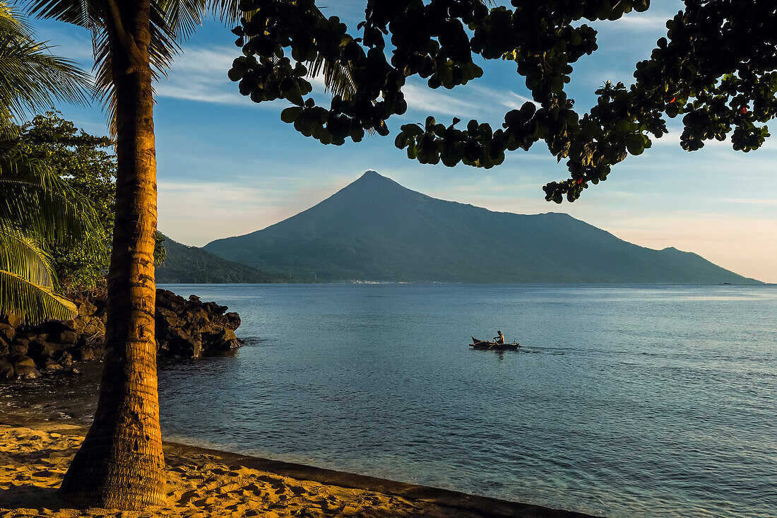 Kalea Beach sunset with palm tree, canoe and Karangetang volcano, Kalea, Siau Island, Sangihe Archipelago, North Sulawesi, Indonesia, Southeast Asia, Asia