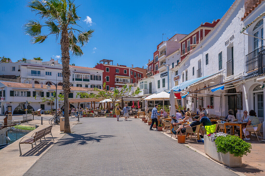 Blick auf bunte Cafés, Restaurants im Hafen vor blauem Himmel, Cales Fonts, Menorca, Balearen, Spanien, Mittelmeer, Europa