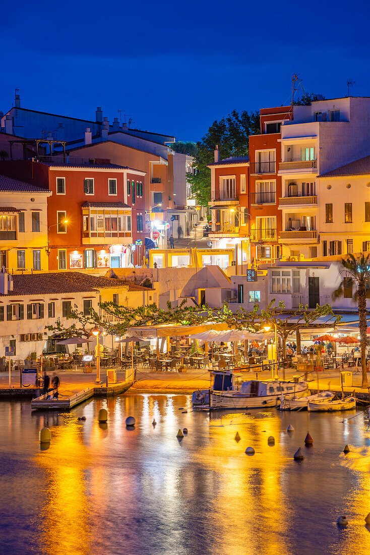 Blick auf Cafés, Restaurants und Boote im Hafen in der Abenddämmerung, Cales Fonts, Es Castell, Menorca, Balearische Inseln, Spanien, Mittelmeer, Europa