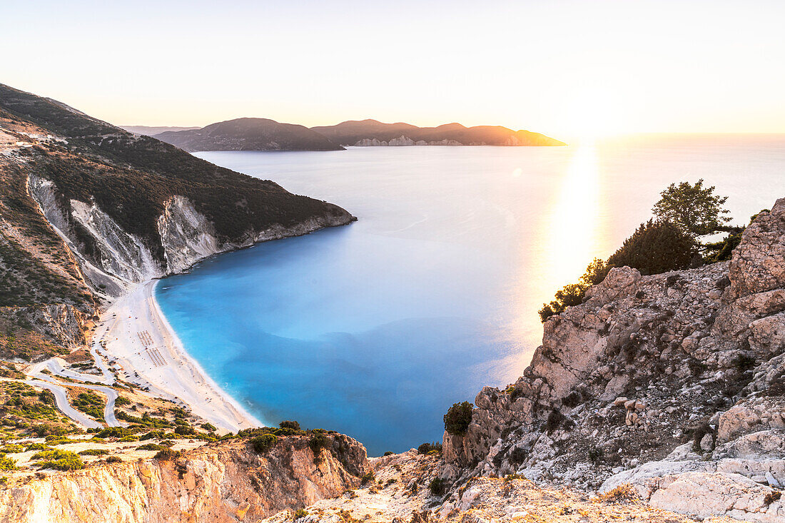 Sunset reflecting in the blue Ionian Sea surrounding Myrtos beach, view from high cliffs, Kefalonia, Greek Islands, Greece, Europe