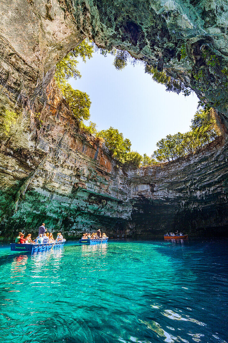 Touristen bewundern die Höhle während einer Bootsfahrt auf dem kristallklaren Wasser des Melissani-Sees, Kefalonia, Ionische Inseln, Griechische Inseln, Griechenland, Europa