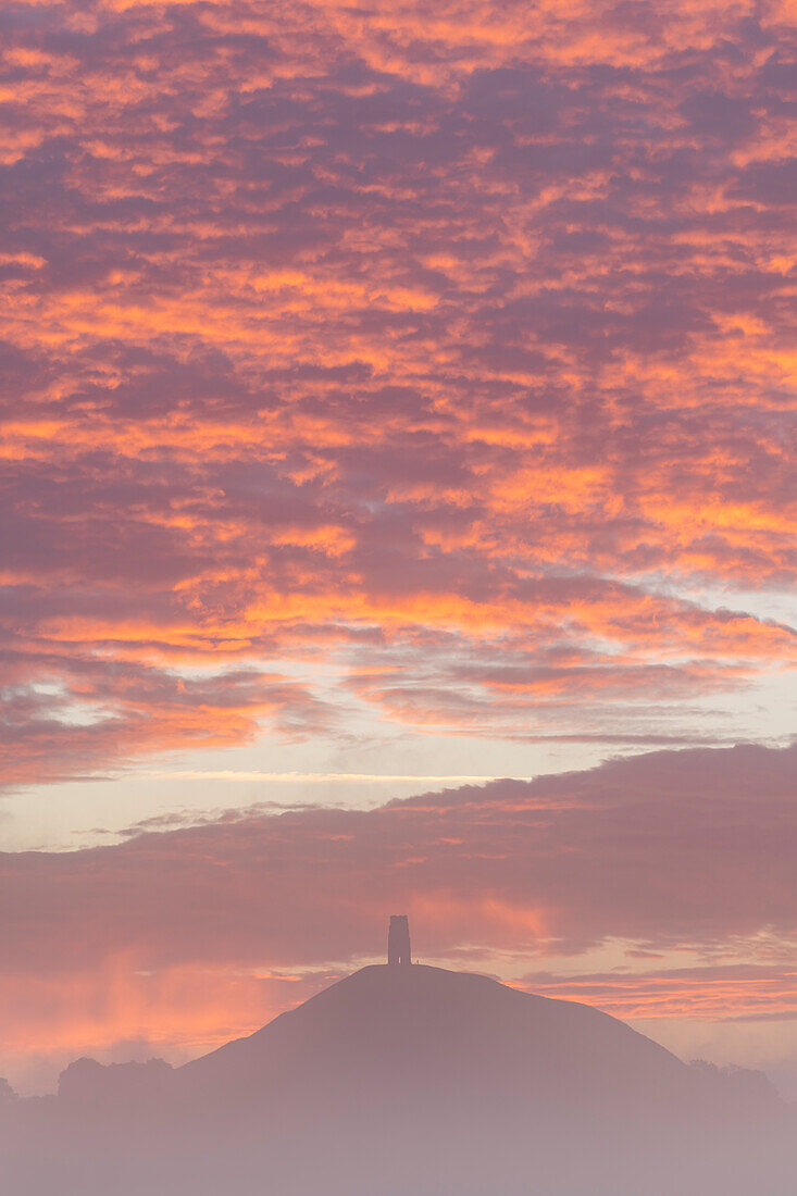 Spektakulärer Sonnenaufgang hinter Glastonbury Tor an einem nebligen Herbstmorgen, Somerset, England, Vereinigtes Königreich, Europa