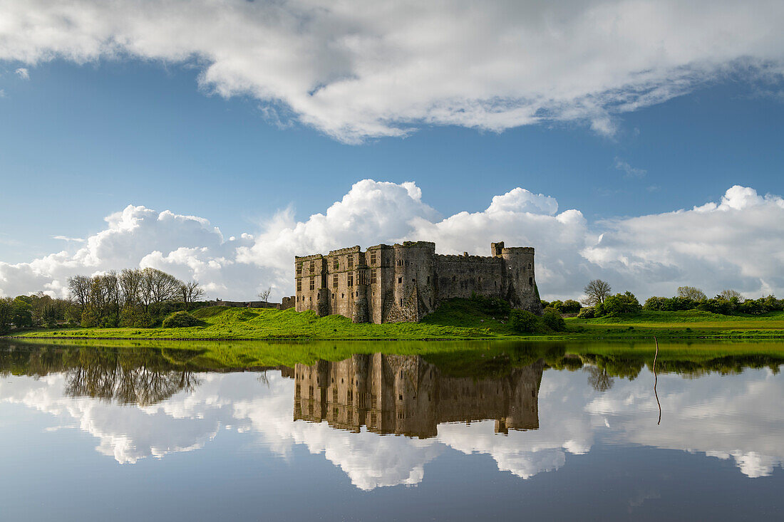 Die prächtigen Ruinen von Carew Castle spiegeln sich im Frühjahr im Mill Pond, Carew, Pembrokeshire, Wales, Vereinigtes Königreich, Europa