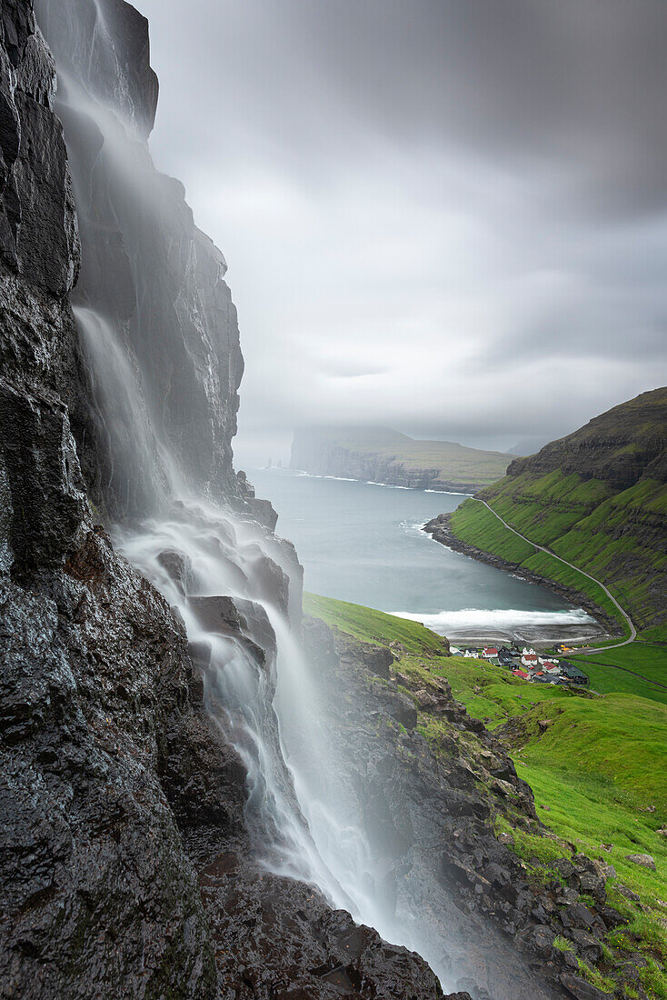 Close up view of the waterfall and the village of Tjornuvik at dusk, Streymoy island, Faroe Islands, Denmark, Europe