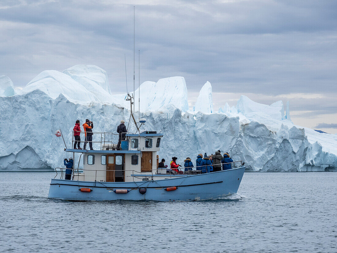 Tourists taking an ice tour in a small boat watching icebergs from the Ilulissat Icefjord, just outside Ilulissat, Greenland, Denmark, Polar Regions