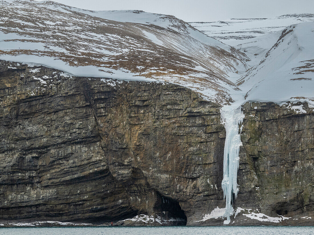 Gefrorener Wasserfall an den Klippen am südlichen Ende der Insel Bjornoya, Svalbard, Norwegen, Europa