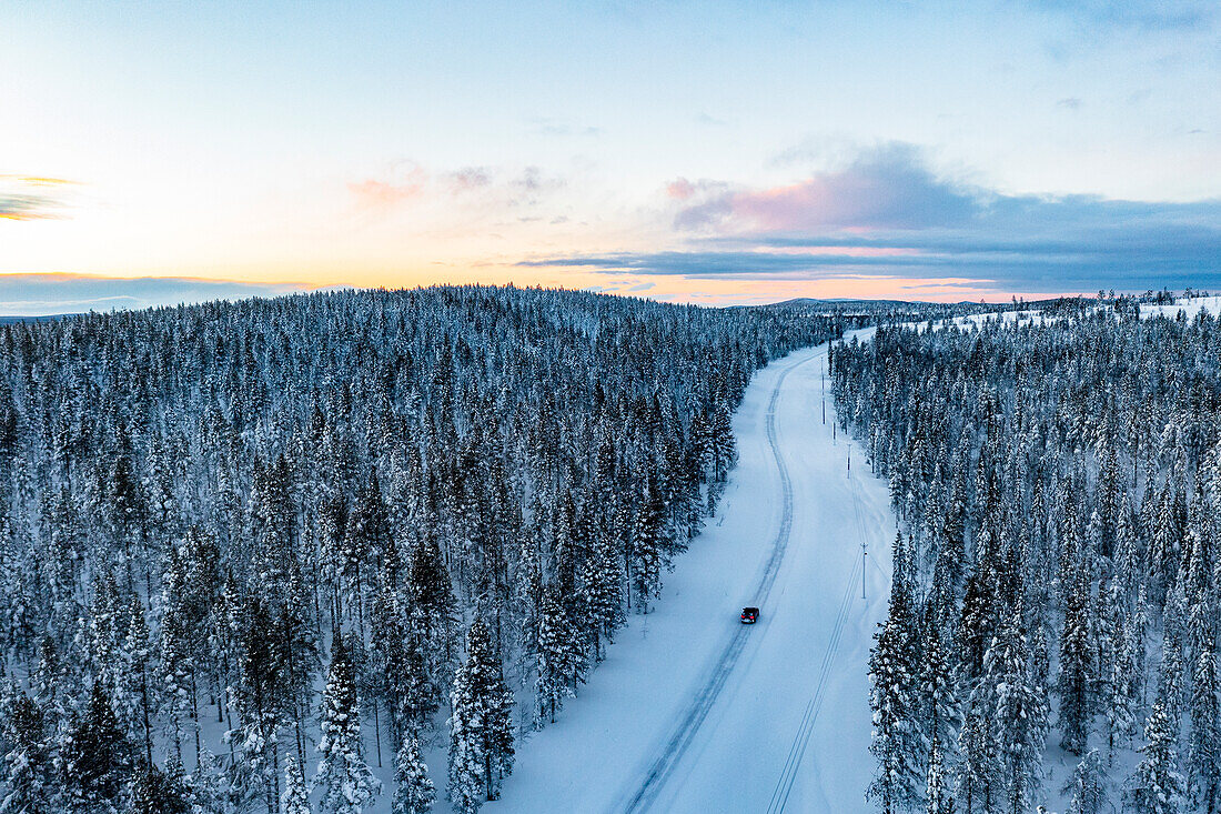 Auto fährt in den verschneiten Wald bei Sonnenuntergang, Luftaufnahme, Gallivare, Norrbotten County, Lappland, Schweden, Skandinavien, Europa