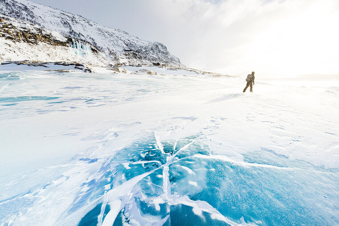 Wanderer erkundet die verschneite Landschaft auf einem vereisten See im Winter, Stora Sjofallet, Norrbotten County, Lappland, Schweden, Skandinavien, Europa
