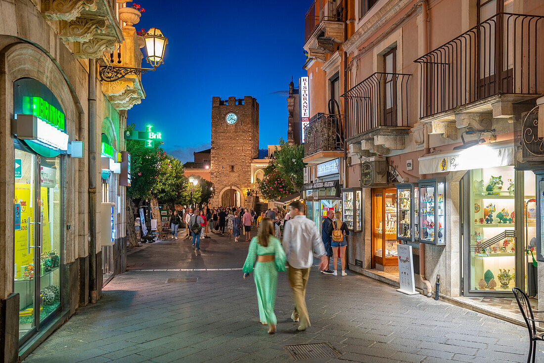 Blick auf Torre dell'Orologio e Porta di Mezzo und belebte Straße in Taormina in der Abenddämmerung, Taormina, Sizilien, Italien, Mittelmeer, Europa