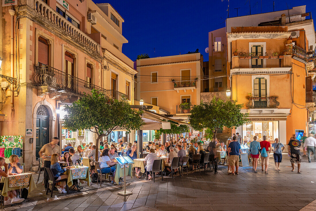 Blick auf Cafés und Restaurants an der belebten Straße in Taormina in der Abenddämmerung, Taormina, Sizilien, Italien, Mittelmeer, Europa