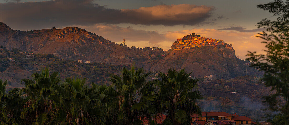 Blick auf die auf einem Hügel gelegene Stadt Castelmola bei Sonnenuntergang von den Giardini Naxos, Taormina, Sizilien, Italien, Mittelmeer, Europa