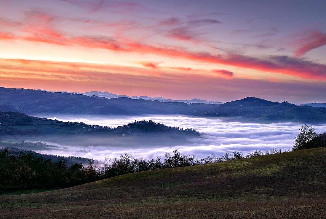 Ein Meer aus Nebel und niedrigen Wolken in einem Tal bei Sonnenuntergang, Italien, Europa