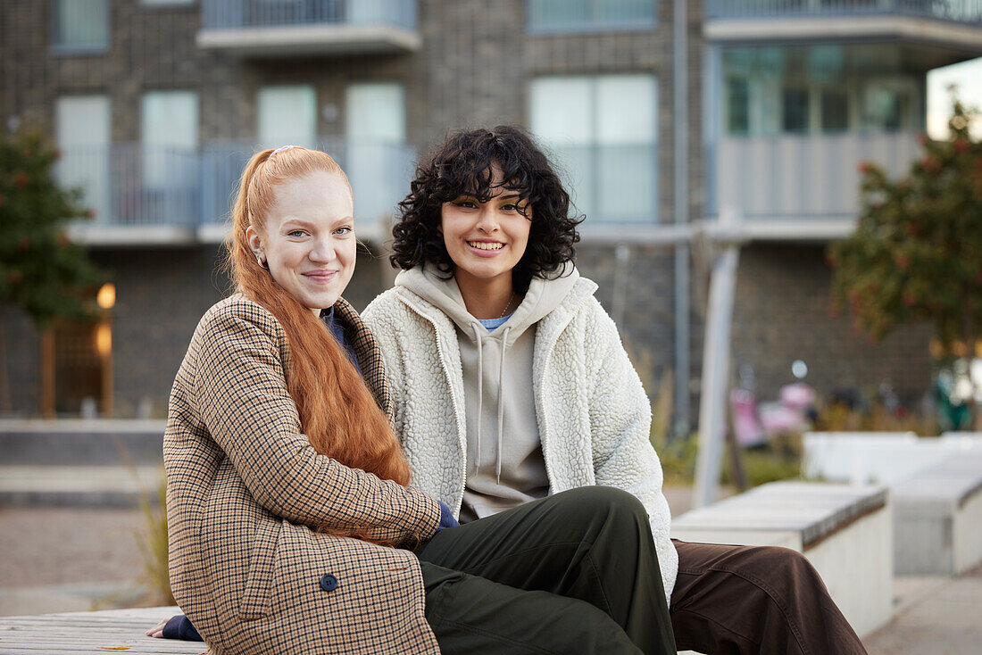 Portrait of young female friends sitting outdoors