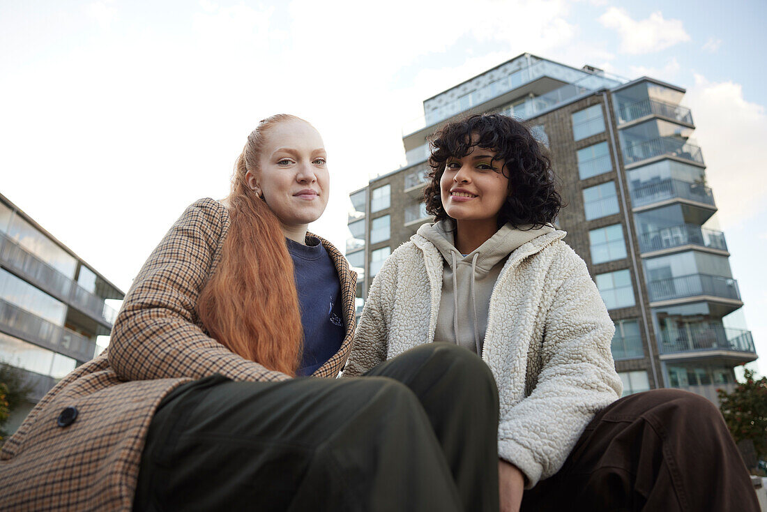 Portrait of young female friends sitting outdoors