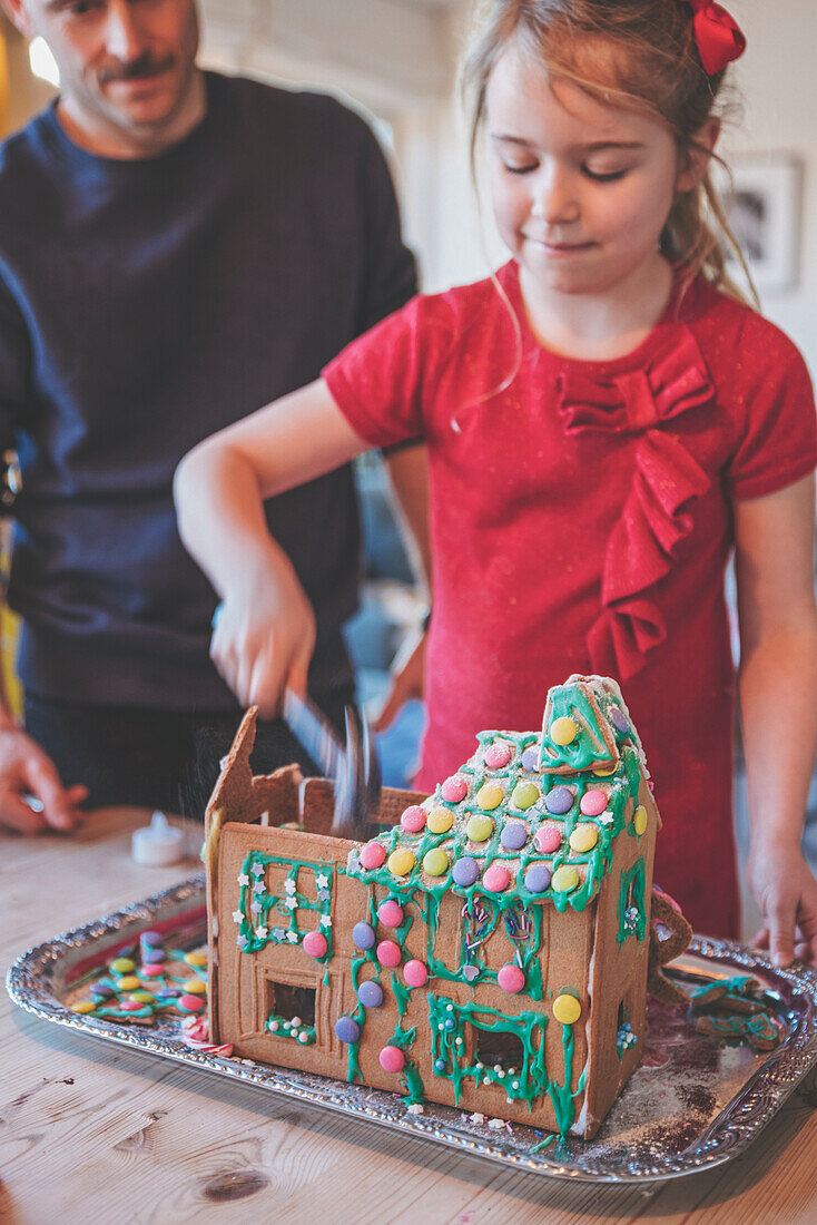 Father and daughter destroying gingerbread house