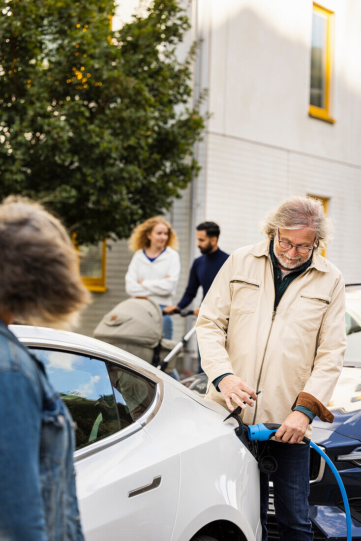 Älterer Mann lädt Elektroauto im Freien auf